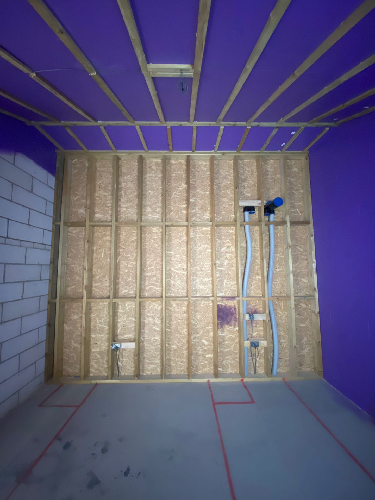 Worker spraying Passive Purple liquid membrane onto wall surfaces during The Dairy Passive House construction to enhance airtightness