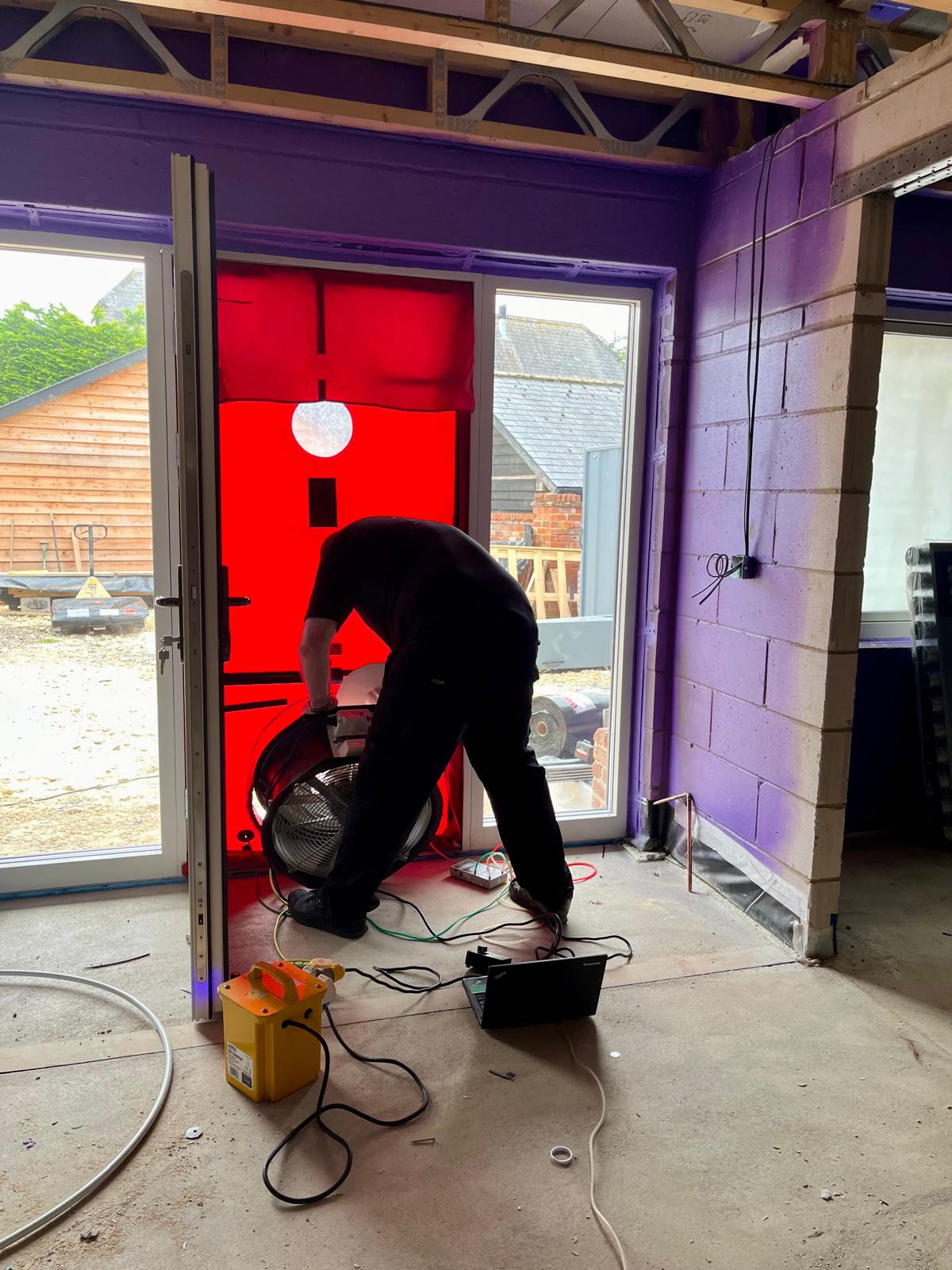 Engineer using blower door equipment to test building airtightness after Passive Purple application for Passive House certification
