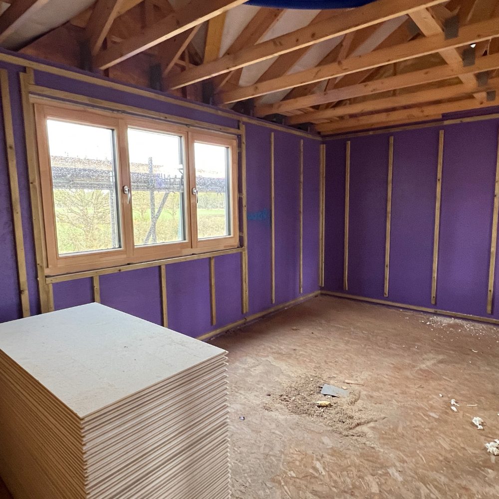 Installer applying Passive Purple membrane to timber frame for maximum airtightness and moisture protection