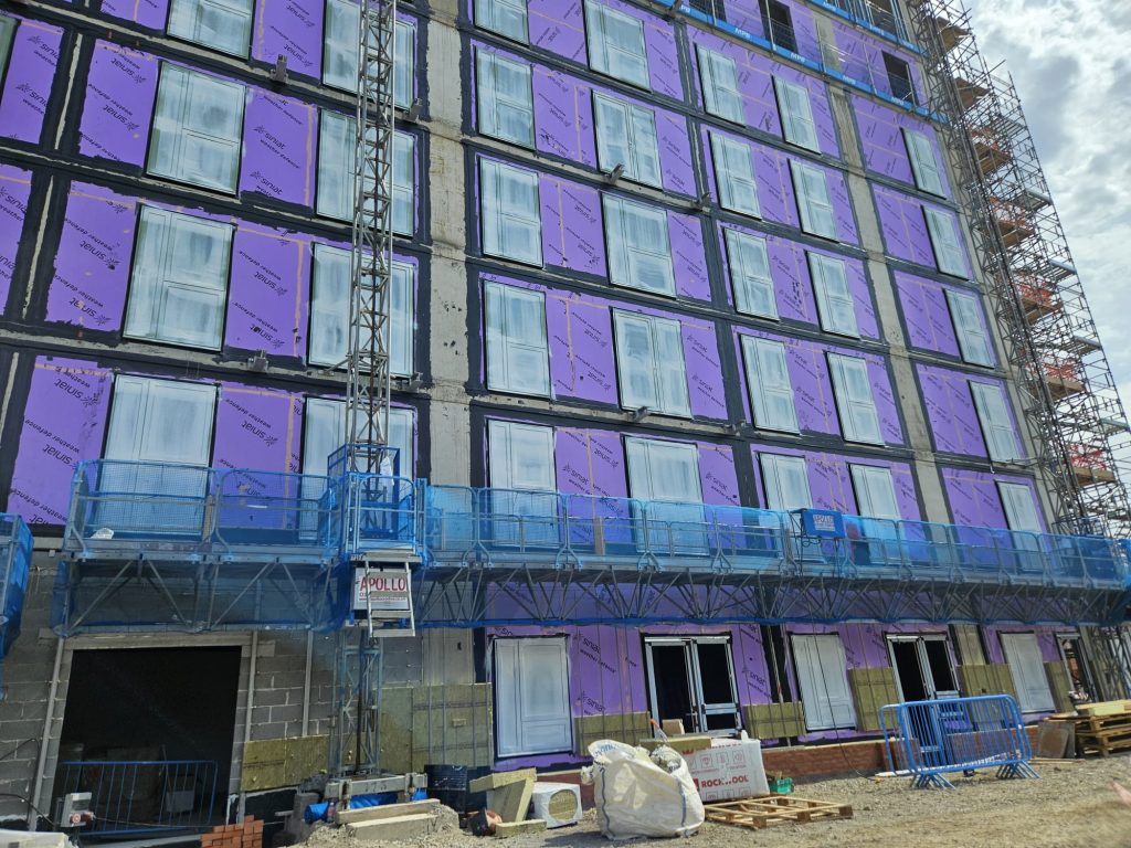 "Spray-on window protection film applied to glazing on a construction site to prevent scratches, paint overspray, and damage, saving time and costs for builders."